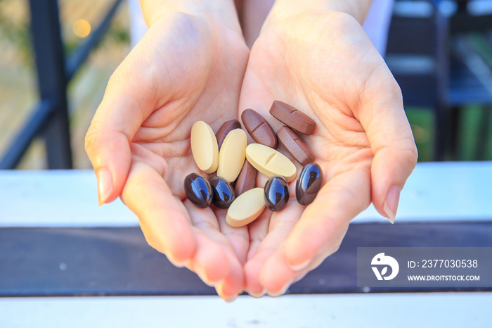 Closeup to multivitamin tablets on two hand of pretty women or girl.