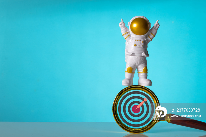 Astronaut standing on magnifying glass with dartboard symbol. Winning, victory and successful symbol.