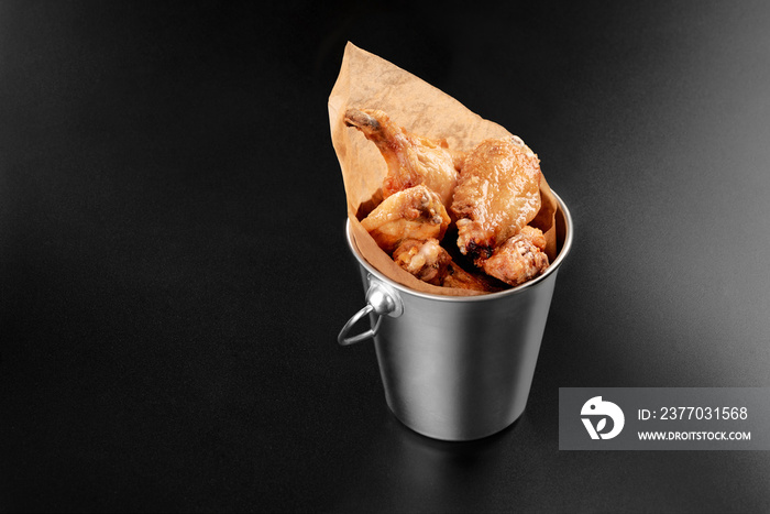 BBQ Chicken wings in a metal bucket onblack background with sauce menu