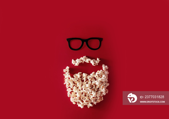 minimalism face with a beard and glasses from popcorn on a red background. funny creative concept of film screening, film industry, film awards, oscar award