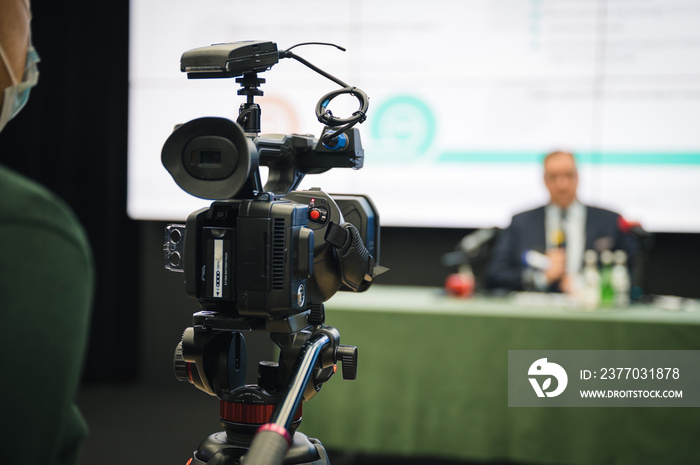 Cameramen during press conference with speaker in the background