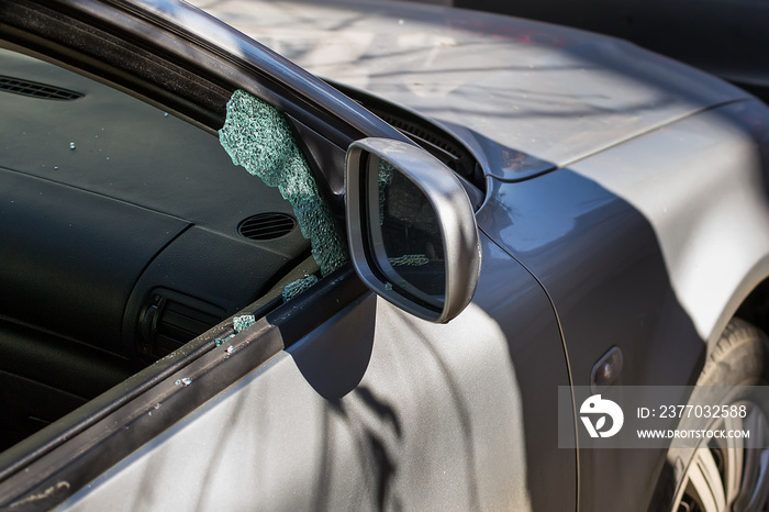 Car window smashed by a thief. Car broken window. Broken right side window of a car parked on the street.