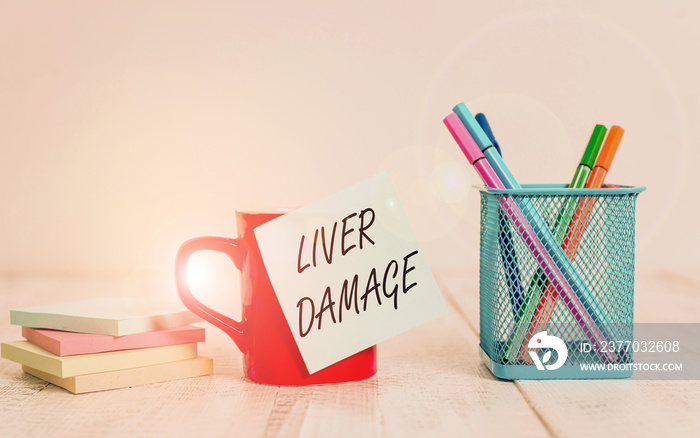 Handwriting text writing Liver Damage. Conceptual photo damage to the liver and its function due to alcohol abuse Coffee cup blank sticky note pens metal holder stacked pads wooden table