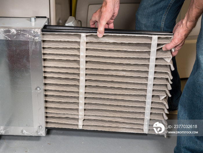 Senior man changing a dirty air filter in a HVAC Furnace