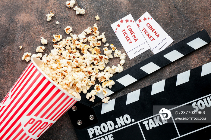 Popcorn, cinema tickets and movie clapper on grunge background