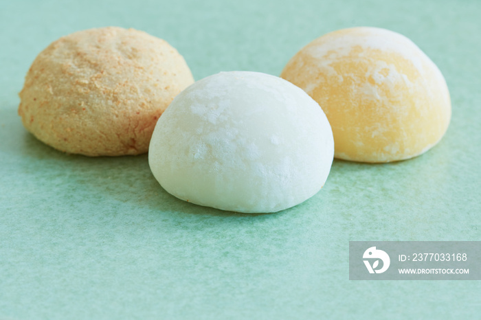 Closeup on three bright colorful mochis on a pastel green plate.