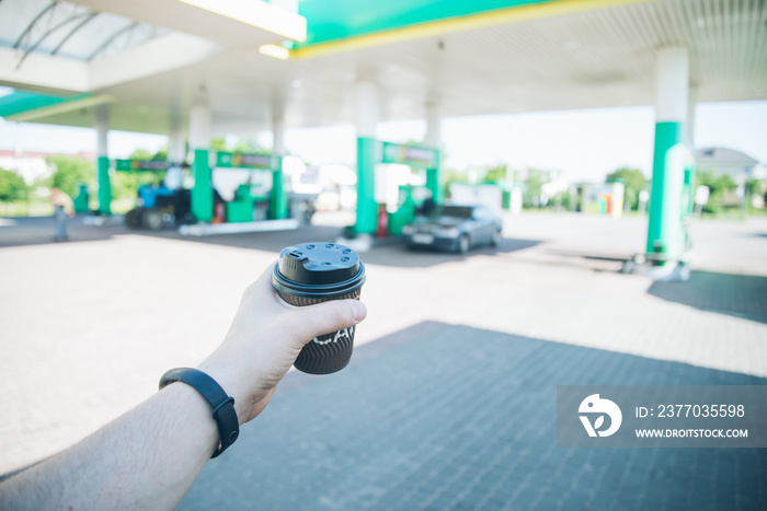 man with coffee cup going to his car on gas station