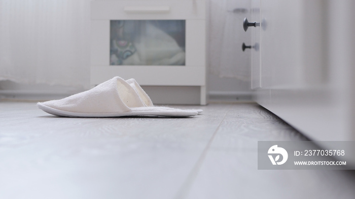 Comfortable White and Fluffy Slippers Waiting in Front of Bed in Bedroom