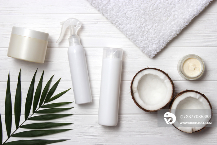 Tropical leaf, care cosmetics and coconut on a wooden table. Top view. Means for hair, body, skin. flatlay