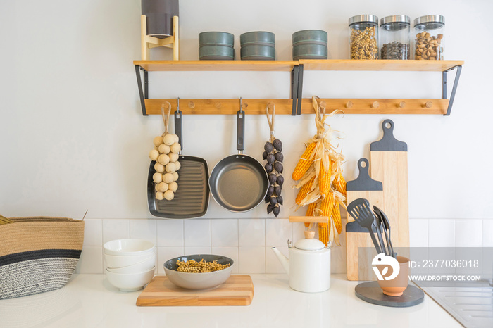 Arrangement of dry food products, spices and ceramics kitchen equipment hanging on country shelves in rustic home kitchen.