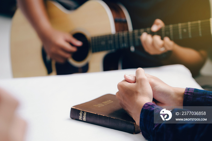 Christian family worship God in home with  playing guitar, and holding holy bible .Group christianity people reading bible together.Concept of wisdom, religion, reading, imagination.