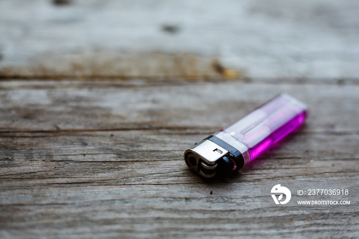 Close up of a pink lighter on a wooden background.