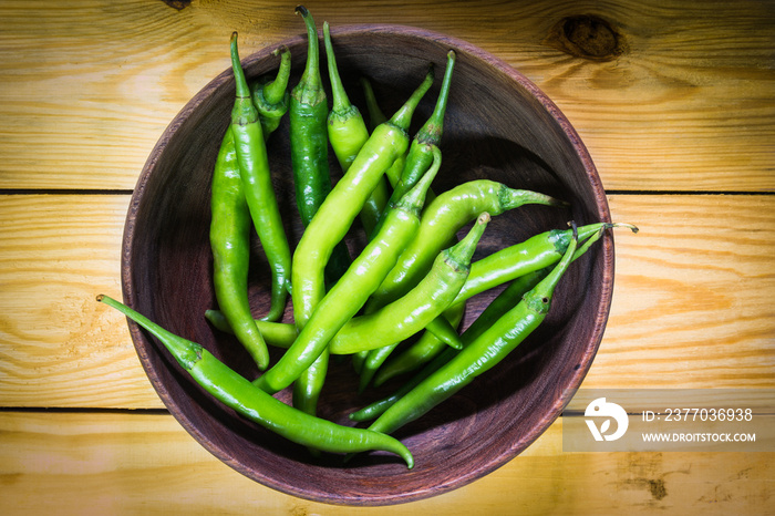 Large green pepper in wood bowl.