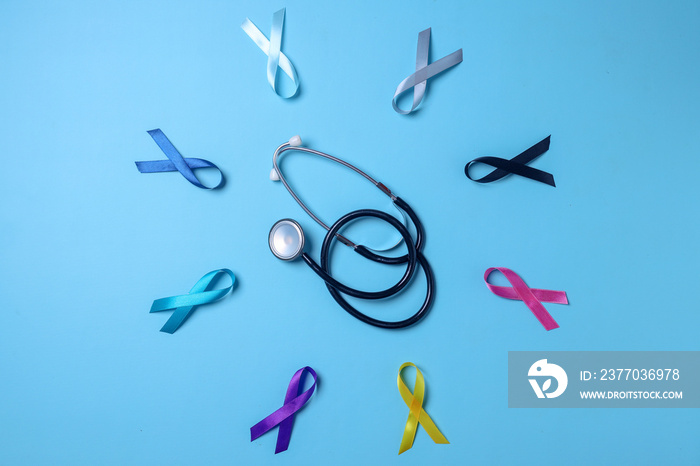 Colorful awareness ribbons surrounding stethoscope on blue background for supporting people living and illness. World cancer day.