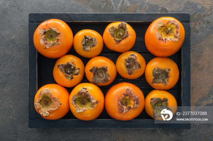 top view of orange and whole persimmons in wooden box