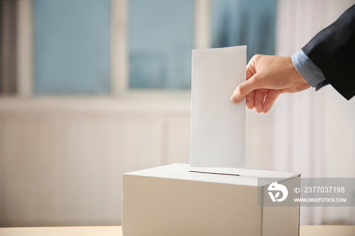 Closeup of hand inserting envelope in ballot box