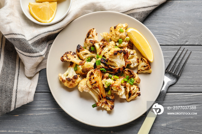 Plate with tasty grilled cauliflower on wooden table