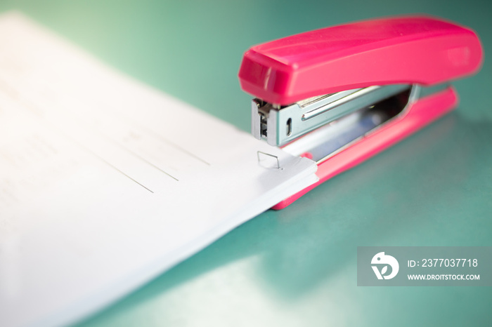 The pink stapler does not pierce through many sheets of paper.shallow focus effect.