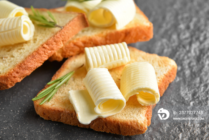 Toasted bread with butter and rosemary on dark background