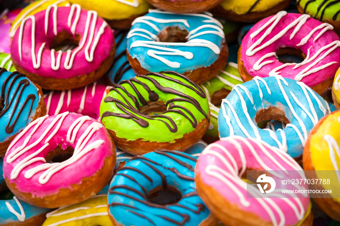 Many colorful donuts, background of different color cakes