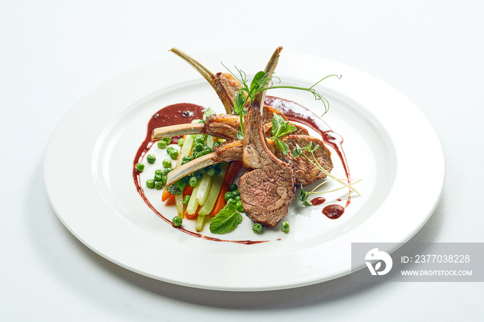 Appetizing grilled rack of lamb with vegetables and berry sauce in a white plate. Grey on white background.