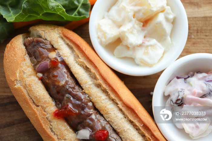 sandwich with sausage. Boerewors roll with relish and salads. South African braai meat with potato salad and coleslaw