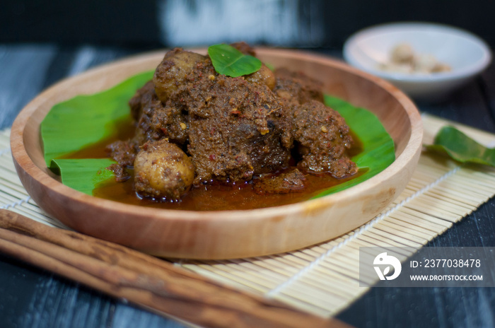 Beef rendang served on a wooden plate and banana leaves