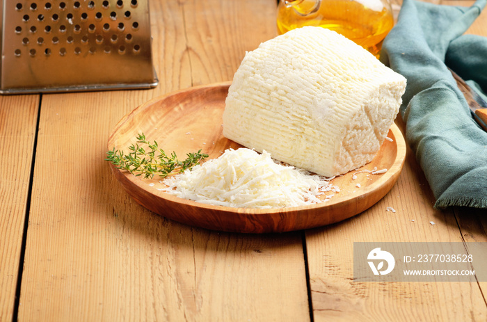 Italian ricotta salted cheese - ricotta salata on rustic wooden background.