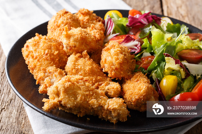 deep-fried chicken wings in breadcrumbs and fresh salad close-up on a plate. horizontal