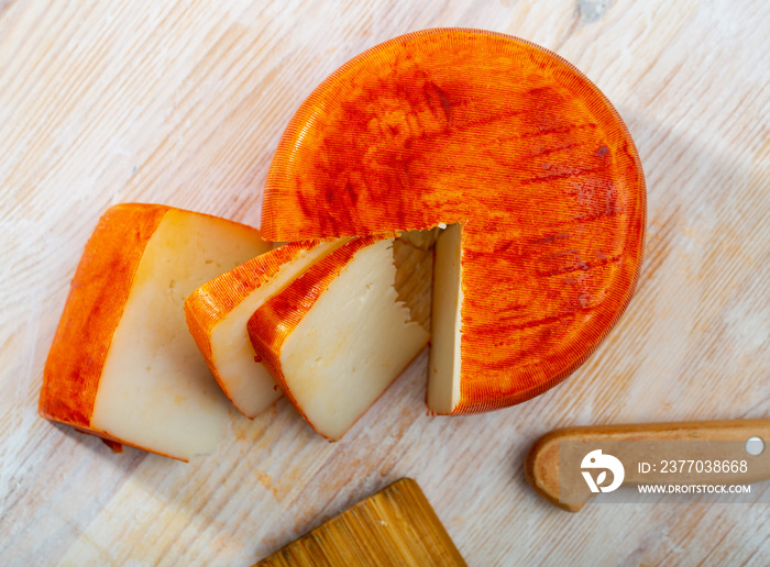 Head of ripened goat cheese with paprika on wooden table