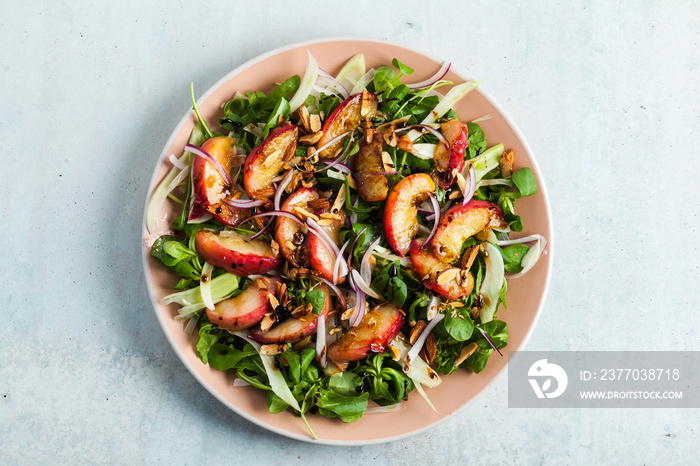 summer, very tasty salad with peaches, sweet onions and arugula with almonds on a table in a plate. simple healthy recipe