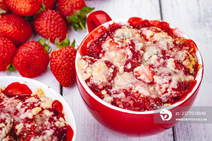 Strawberry crumble in cup on wooden rustic table. Close up