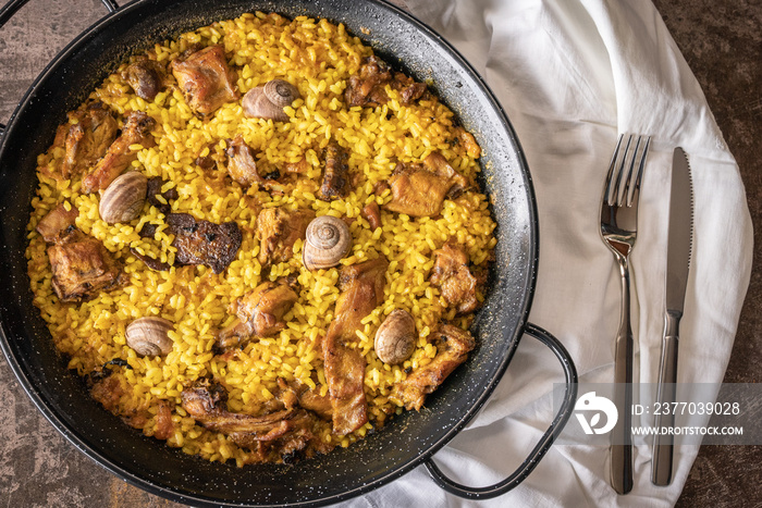 Top view of a rice paella with bush meat and snails.