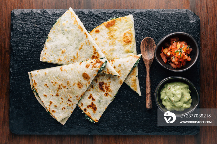 ฺTop view of Baked Spinach and Cheese Quesadillas served with Salsa and Guacamole.