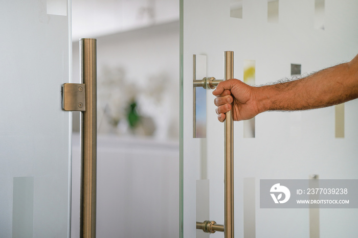 Male hand open the office glass door. Man hand prepare to open glass door to entering an office background