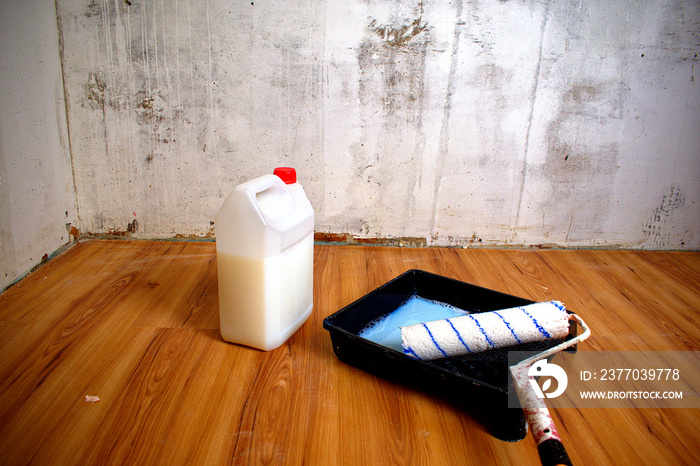 Roller, tray and plastic bottle with white primer. Preparation of walls, covering the walls with primer. Renovation concept.