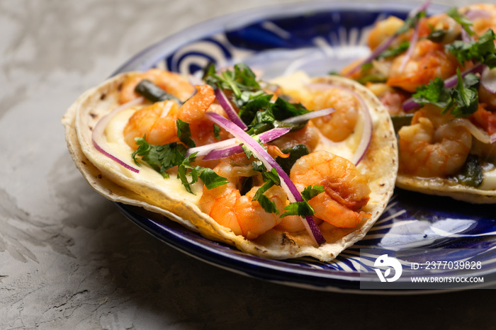 Mexican food. Shrimp tacos with melted cheese and poblano pepper called gobernador on grey background.