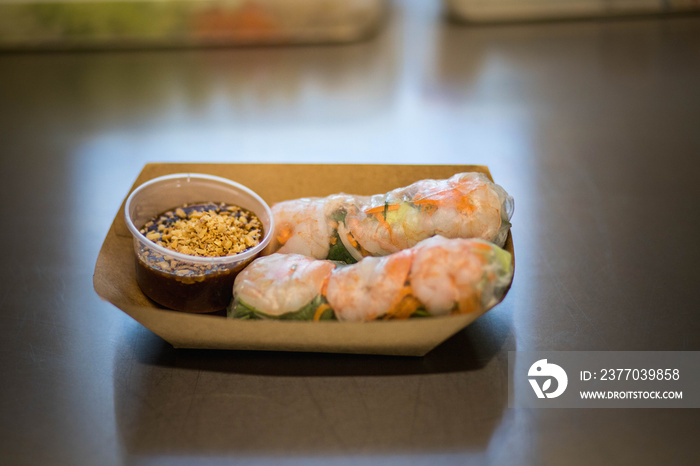 Présentation de rouleaux de printemps avec une sauce dans une barquette en carton