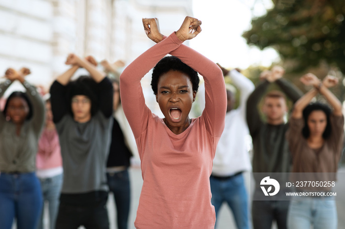 Woman with clenched fists above head protesting with group