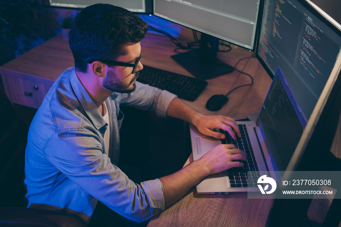 Profile photo of it specialist guy working late at night sitting comfy office chair holding hands on keyboard looking monitors website debugging expert dark office indoors