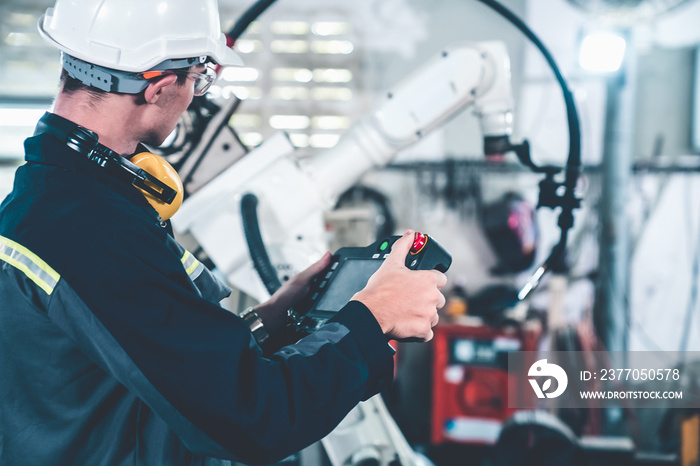 Young factory worker working with adept robotic arm in a workshop . Industry robot programming software for automated manufacturing technology .