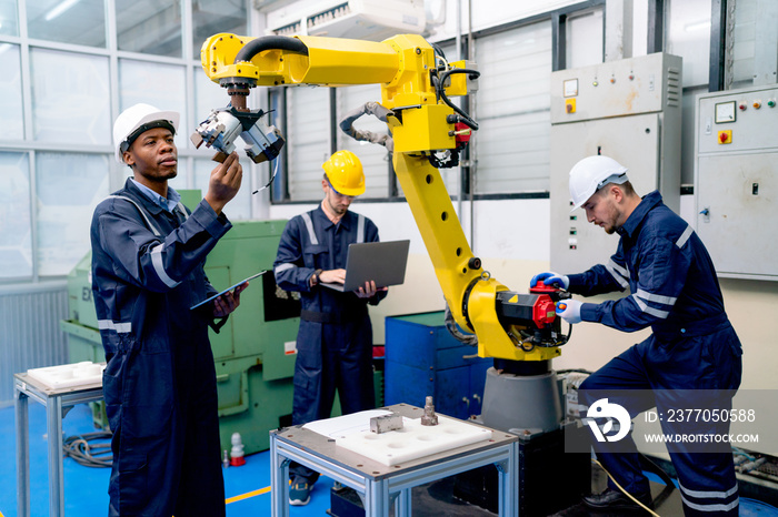 African American technician work with his team to check and maintenance robotic arm in factory workplace.