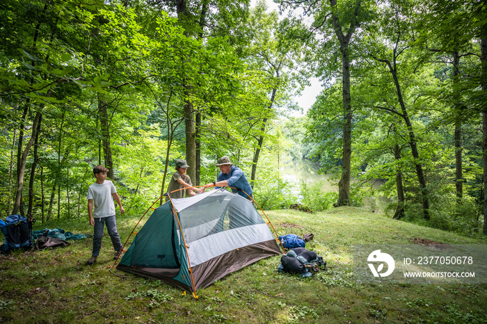 Air Force service member sets up a tent with his sons on  a backpacking trip.