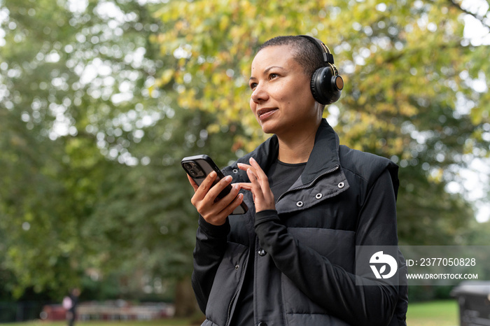 Woman with headphones and smart phone in park