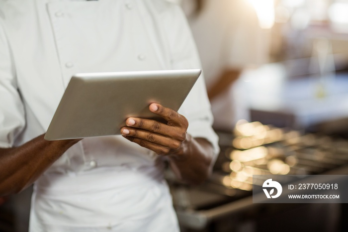 Mid section of chef using digital tablet