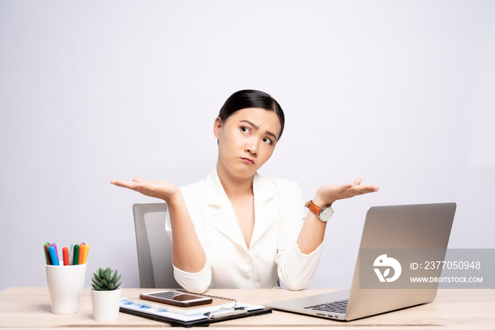 Portrait of a confused woman sitting at office isolated over background