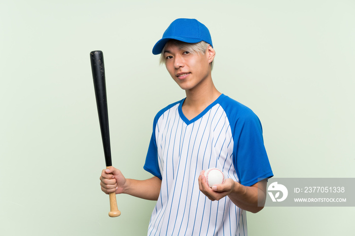 Young asian man playing baseball over isolated green background