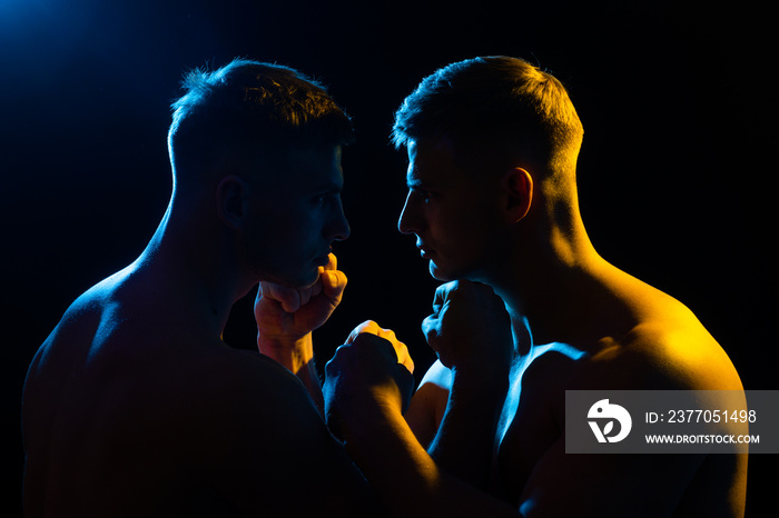 Aggressive man. Confrontation. Two brutal man looking into each others isolated on black.