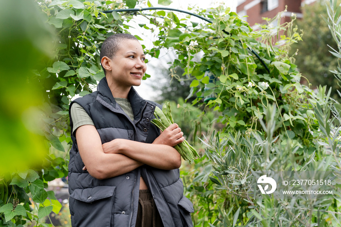 Portrait of woman with bunch of homegrown green bean in urban garden