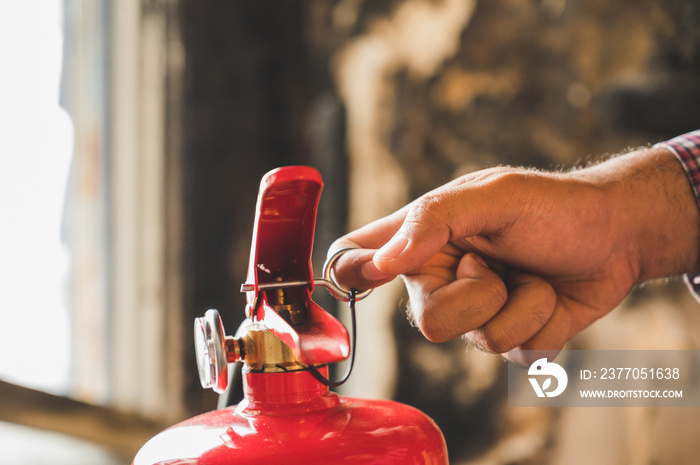 Close up hand Fireman using fire extinguisher fighting. Hand pulling pin of fire extinguisher